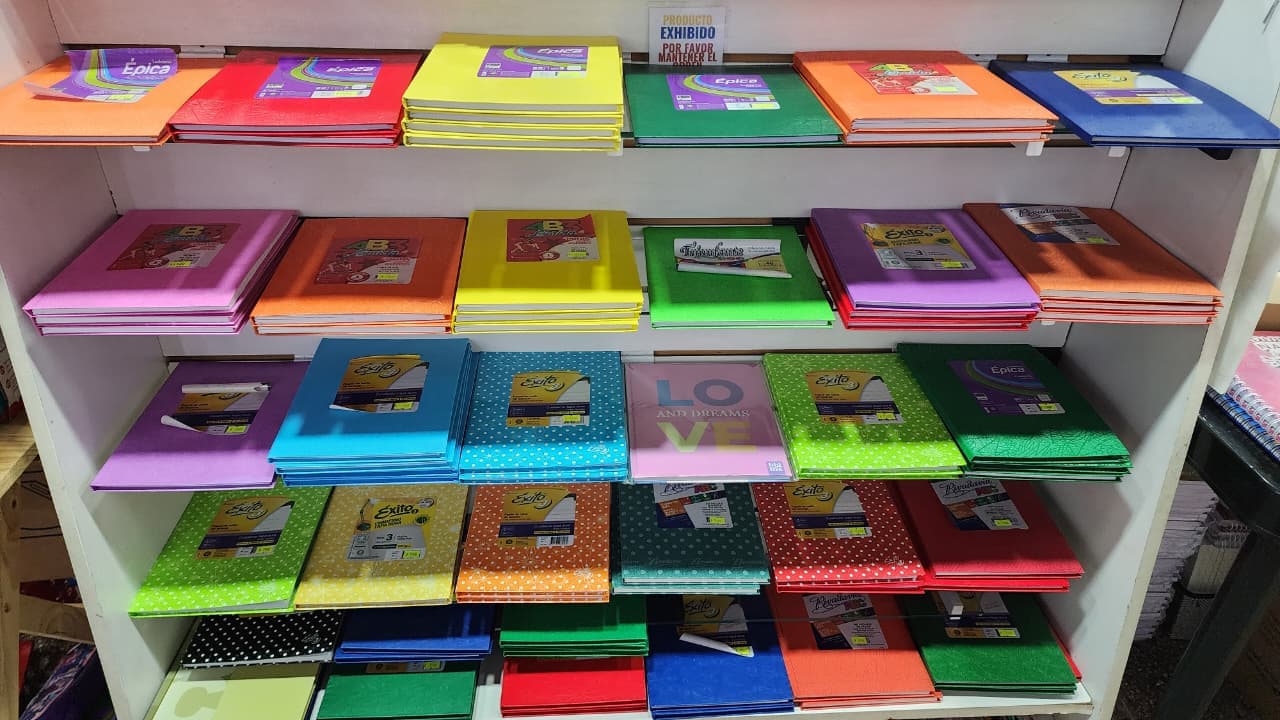 Estantería de cuadernos escolares forrados de todos los colores en Librería Arcoíris