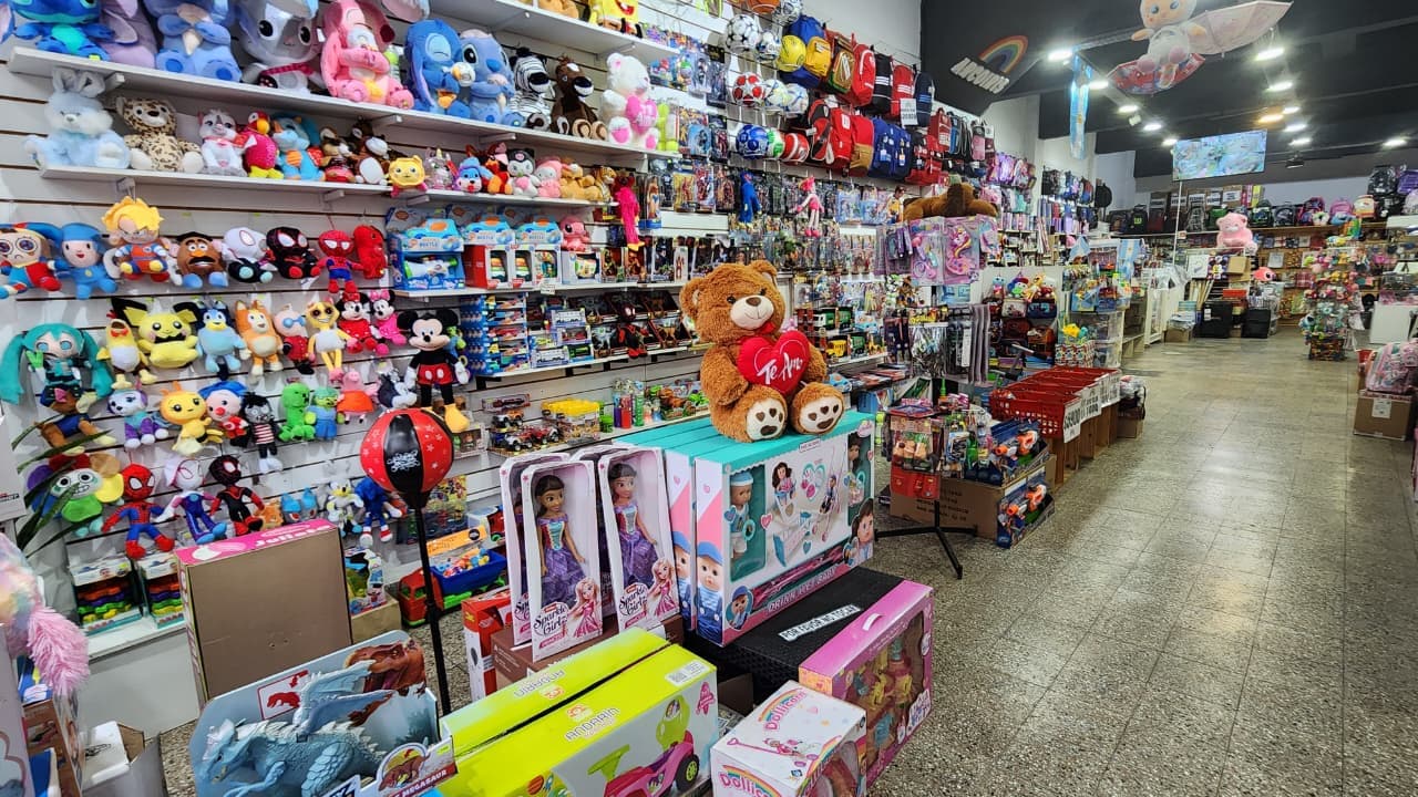 Sector de juguetería en Librería Arcoíris: pared de peluches, juegos y muñecas